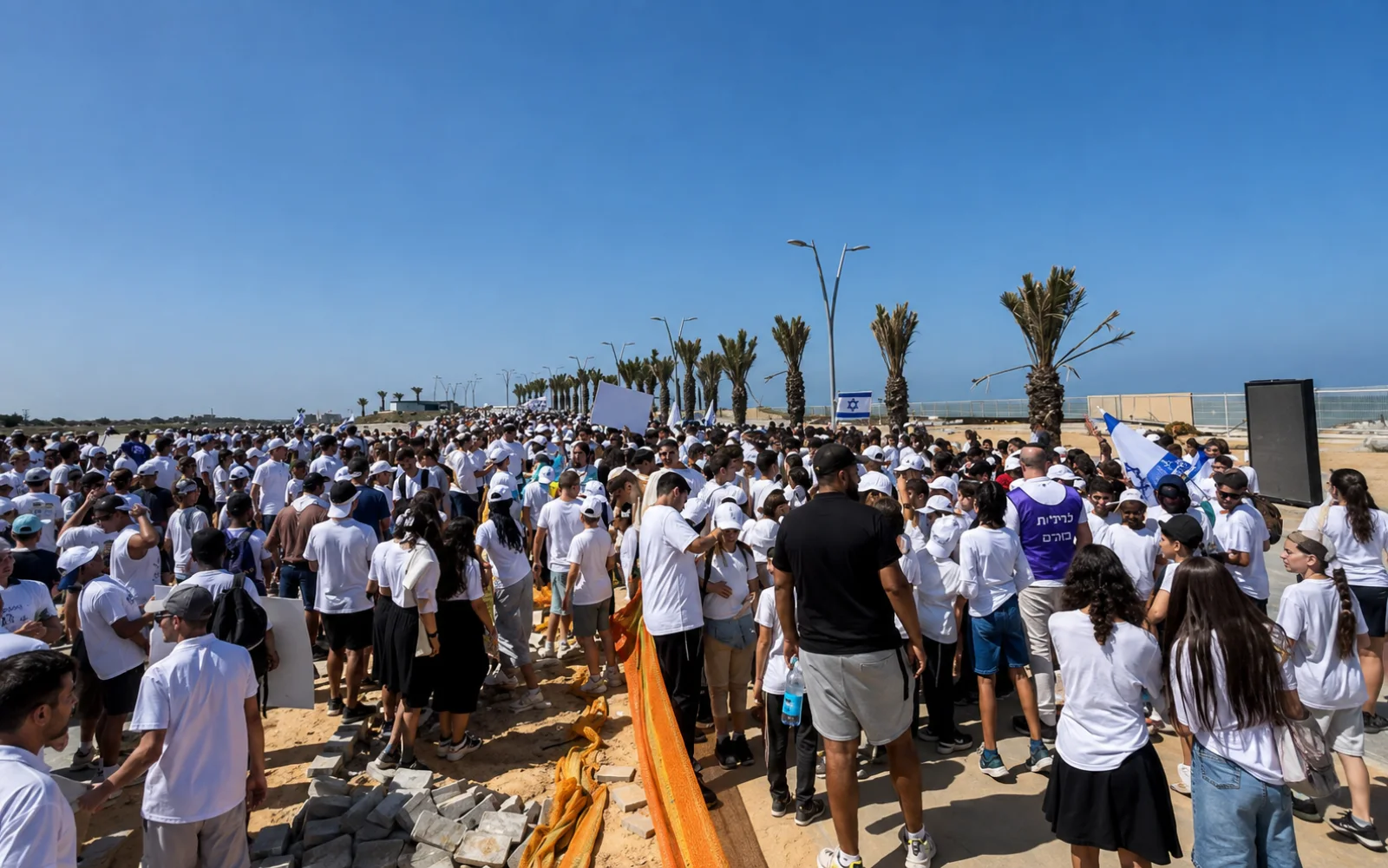 קהל גדול עומד באירוע בשטח פתוח לצד מסך ומערכת כריזה